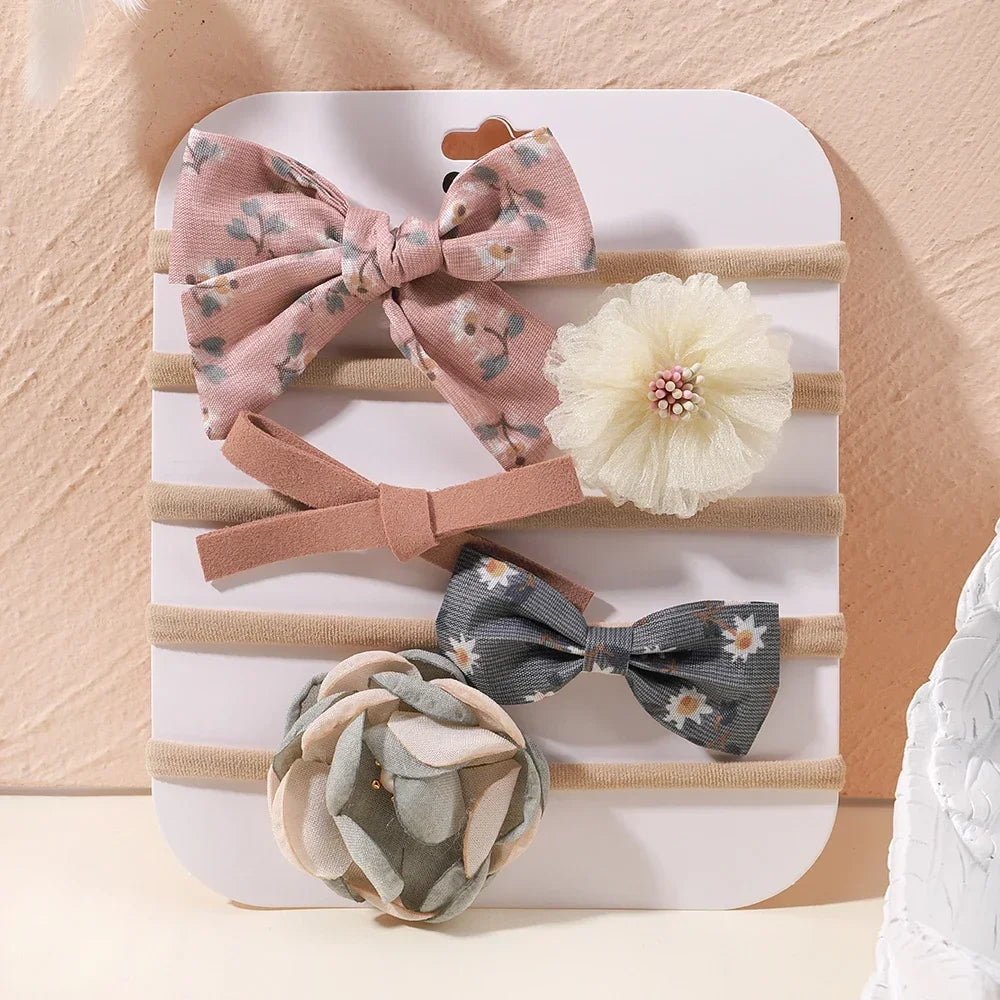 Set of 5 baby headbands with floral lace and bow designs in pink, gray, and beige.