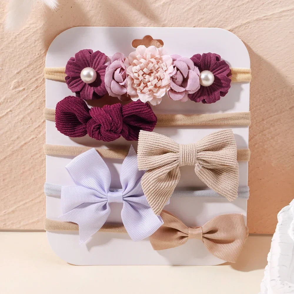 Set of 5 baby headbands with lace flowers and bows in shades of purple, beige, and light blue.
