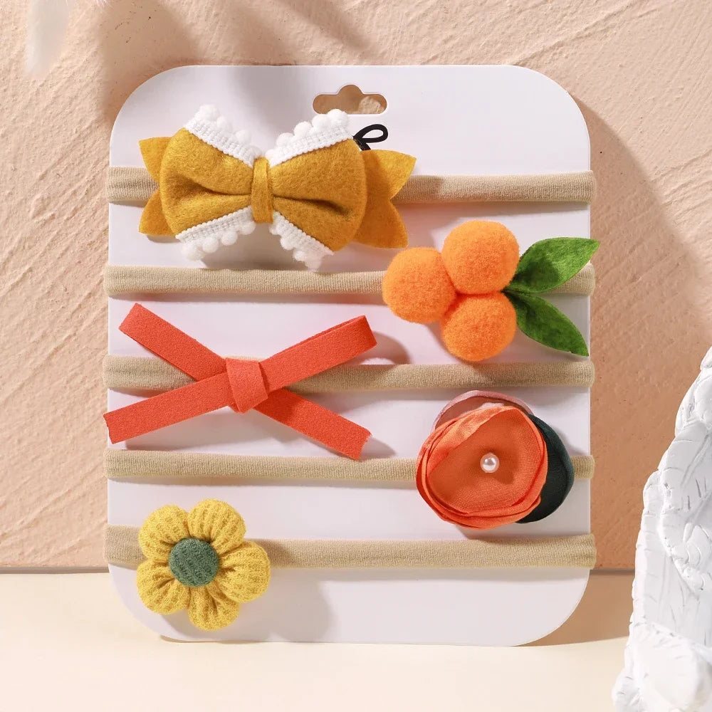 Set of 5 baby headbands with yellow bow, orange fruit, red bow, orange flower, and yellow flower designs.