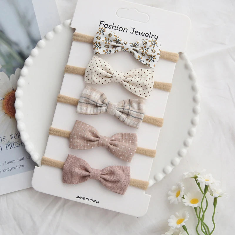 Set of 5 handmade cotton baby headbands with bows in floral, polka dot, plaid, and solid pink designs.