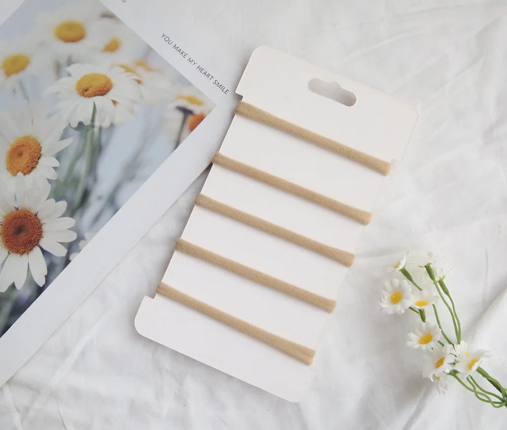 Set of six beige elastic cotton headbands for babies and toddlers, displayed on a white card.