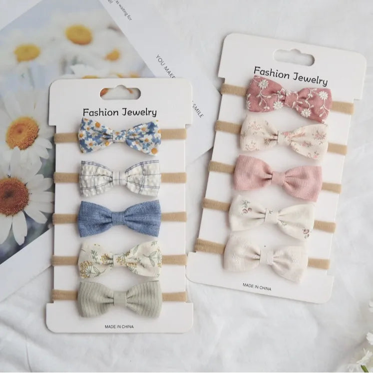 Sets of five soft cotton baby headbands with various floral and solid bow designs in pastel colors.