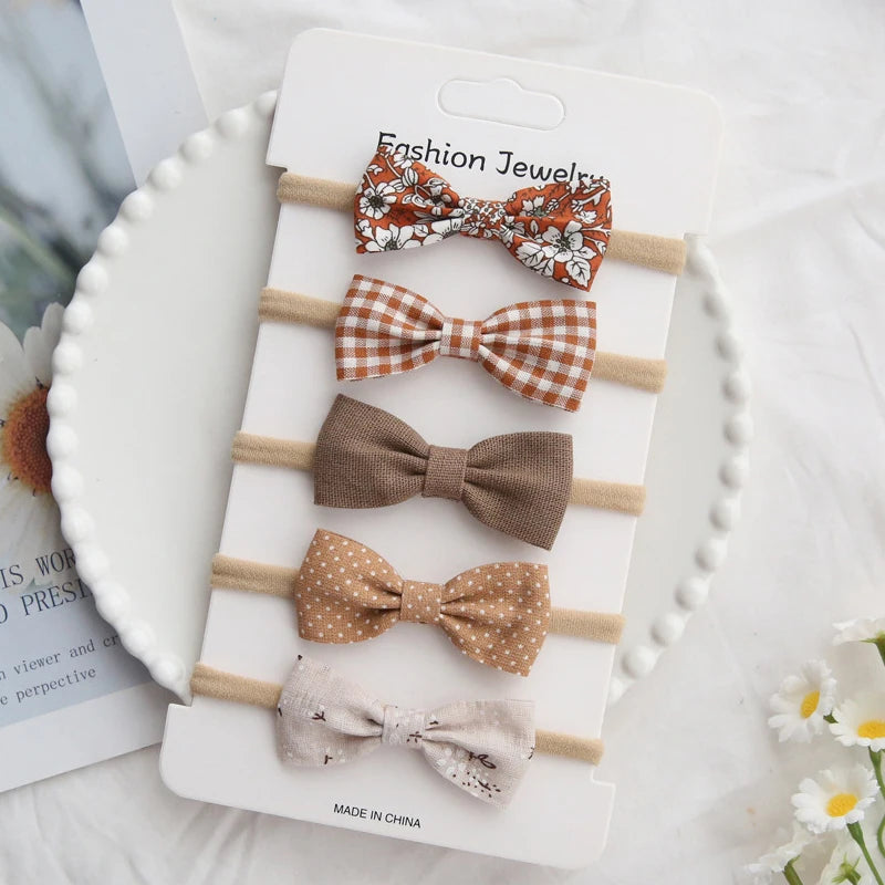 Set of five handmade baby girl headbands with bows in various brown, floral, plaid, and polka dot cotton designs.