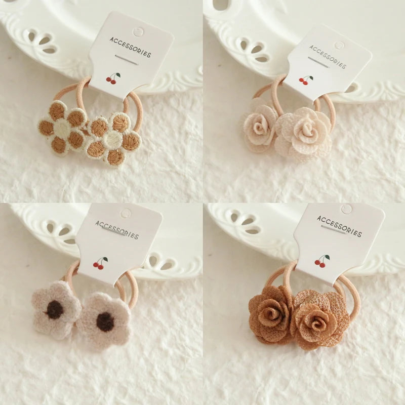 Four sets of soft cotton hair ties for babies and girls, featuring delicate floral designs in neutral and brown tones.