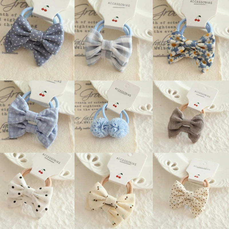 Nine soft cotton hair bows and scrunchies for babies and girls, featuring various patterns like polka dots, plaid, and floral.