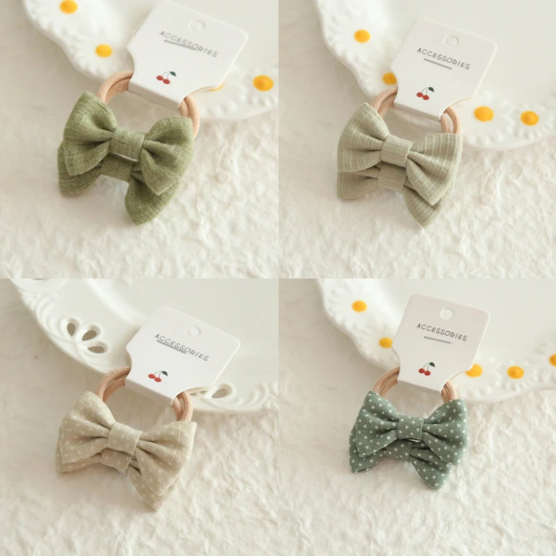 Four soft cotton bow hair ties for babies and girls: two solid green, one beige, and one green with white polka dots.
