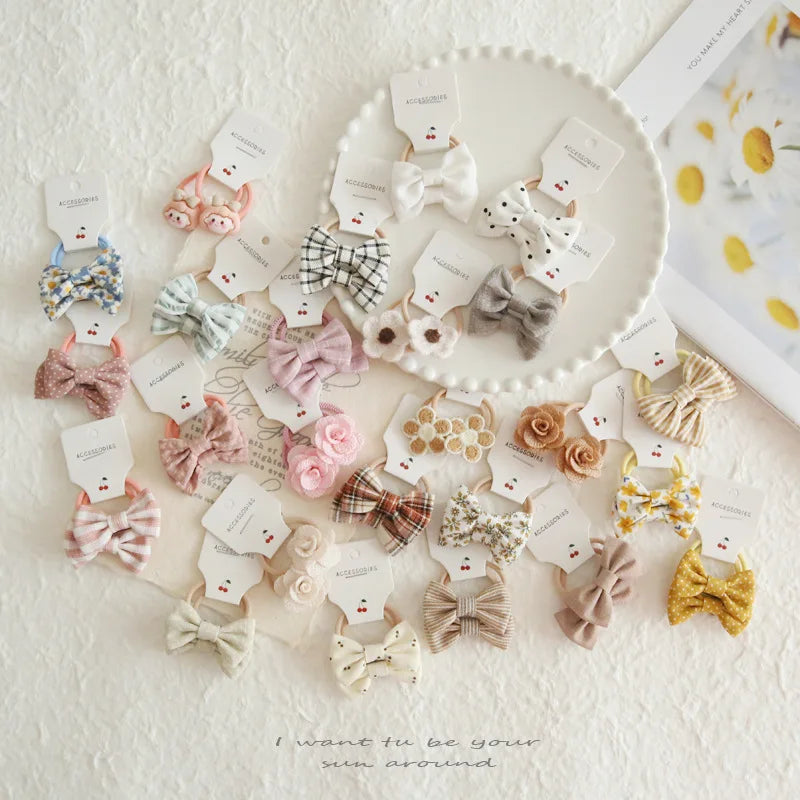 Assortment of soft cotton hair bows and elastic ties for babies and girls in various colors and patterns.