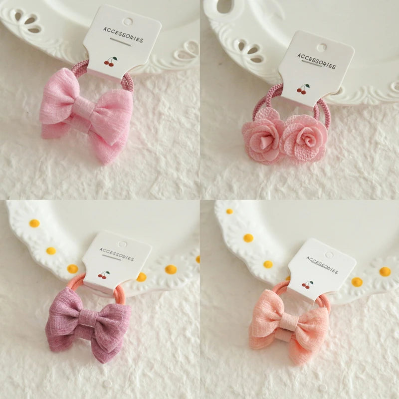 Four soft cotton hair ties for babies and girls: pink bow, pink roses, purple bow, and peach bow.