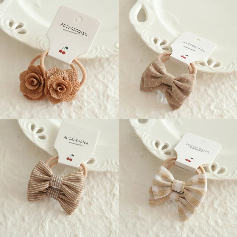 Set of four gentle hair ties for babies and girls: two with fabric flowers, two with patterned bows.