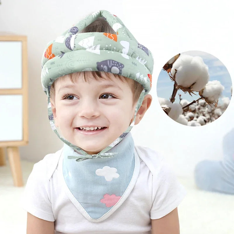 Adjustable, breathable baby safety helmet in light green with forest animal print, worn by a smiling toddler.