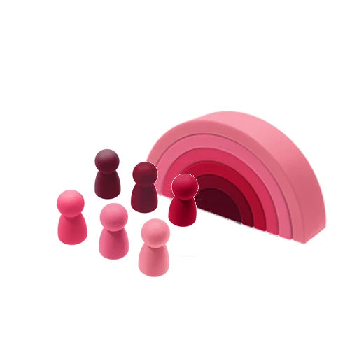 Soft pink silicone stacking rainbow toy with six matching peg dolls in varying shades of pink and red.