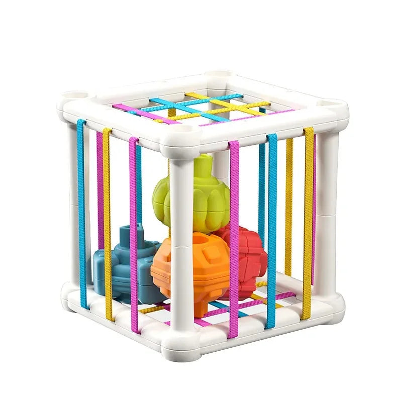 Montessori shape sorter cube with colorful elastic bands and four textured shapes in green, blue, orange, and red.