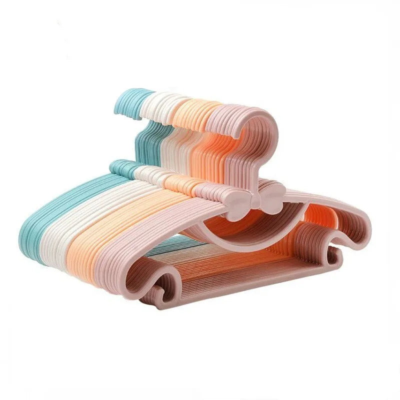Stack of colorful pastel plastic baby clothes hangers with bow details.