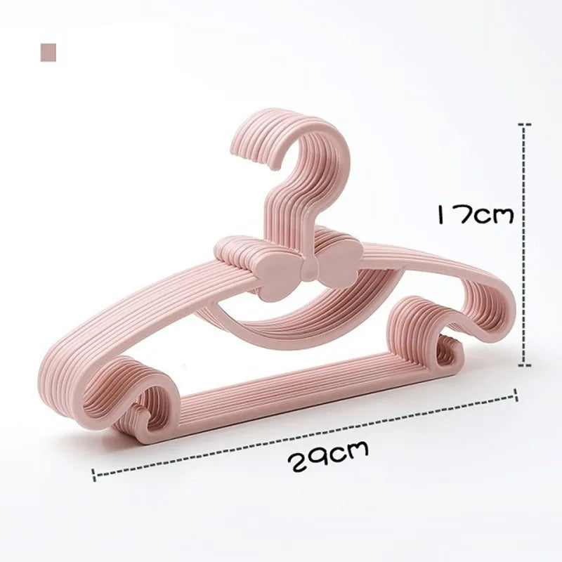 Pink plastic baby clothes hangers with a decorative bow and dimensions 29x17cm.
