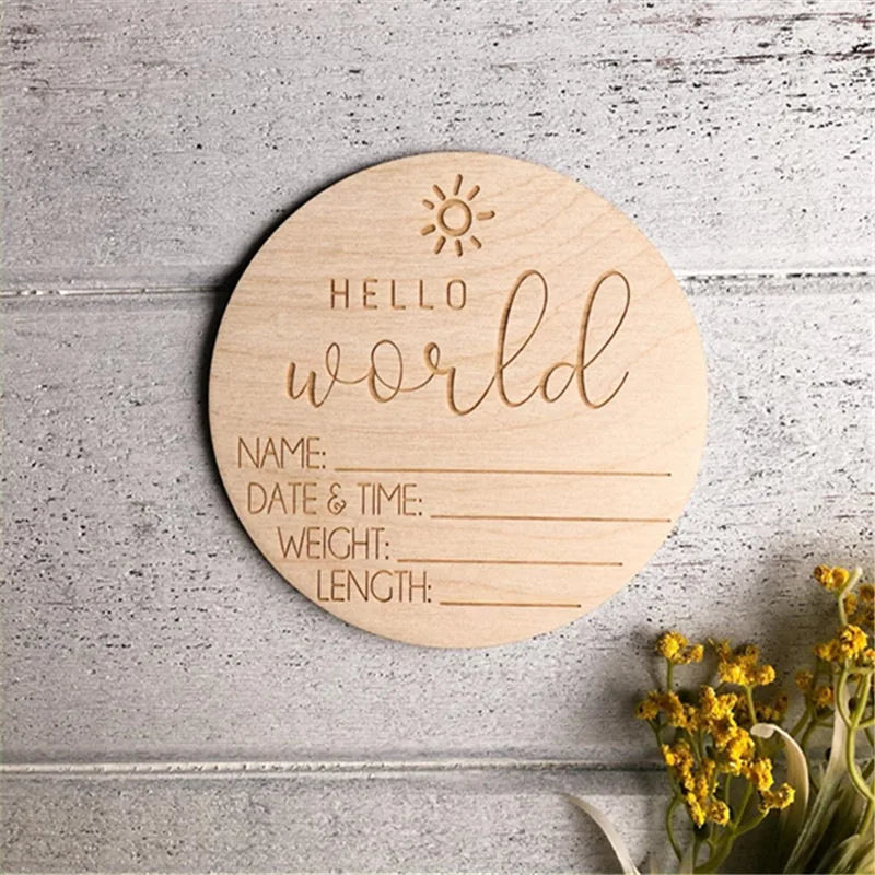 Round wooden "Hello World" baby birth announcement sign with engraved details for name, date, weight, and length.