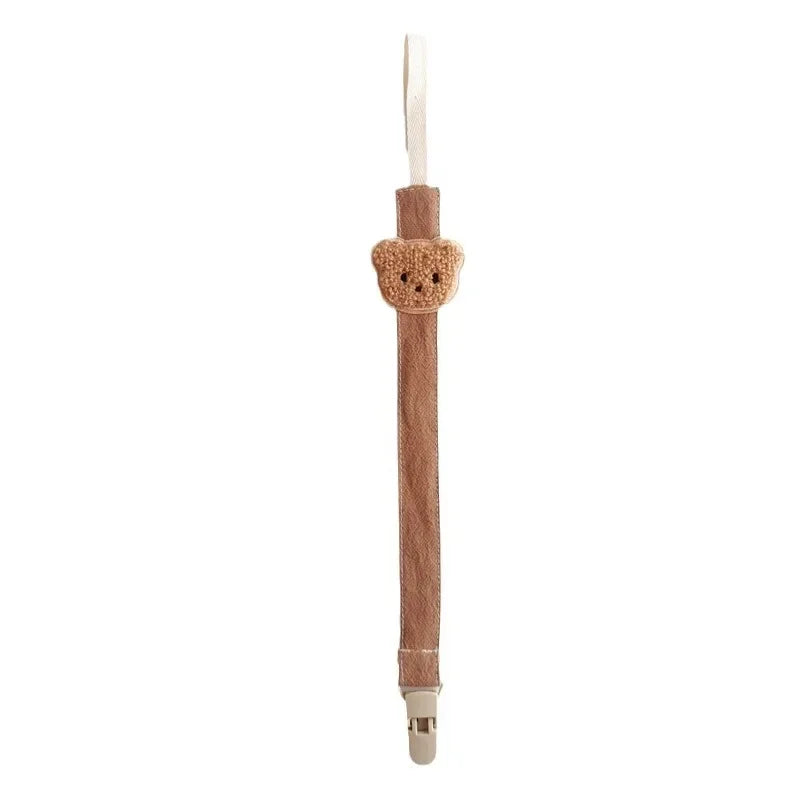 Brown cotton pacifier clip with an embroidered teddy bear design and plastic clasp.
