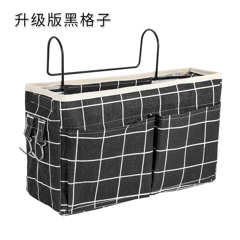 Black and white plaid cotton fabric bedside organizer with multiple pockets and metal hooks.