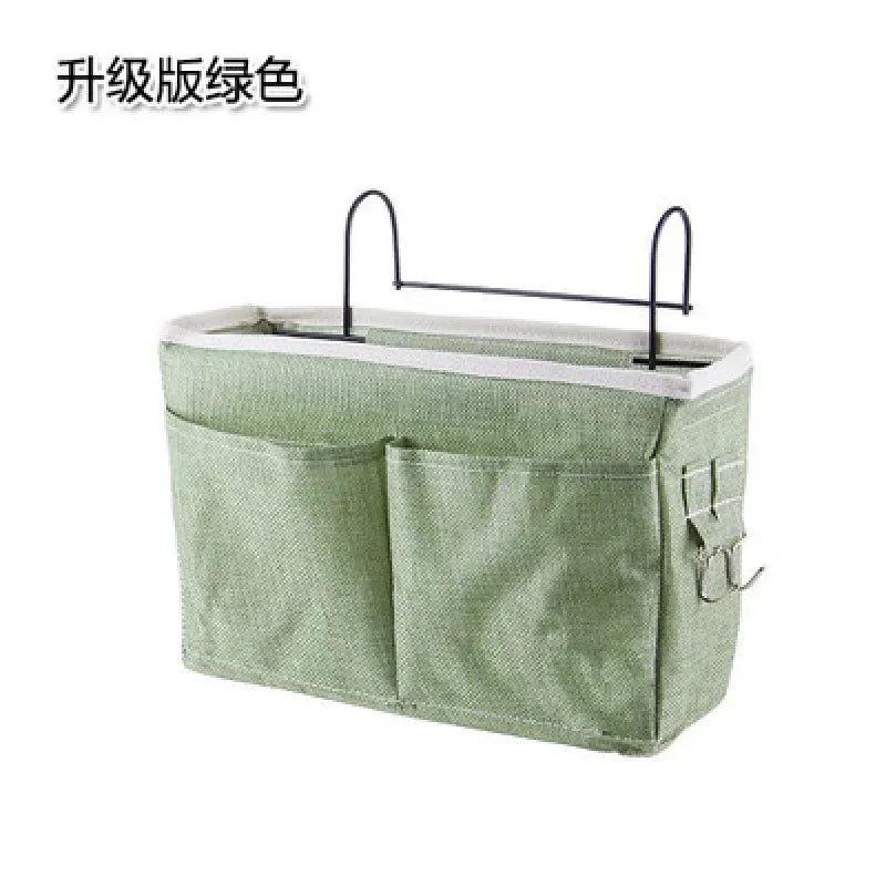 Green multi-compartment cotton fabric bedside organizer with metal hooks for baby essentials.