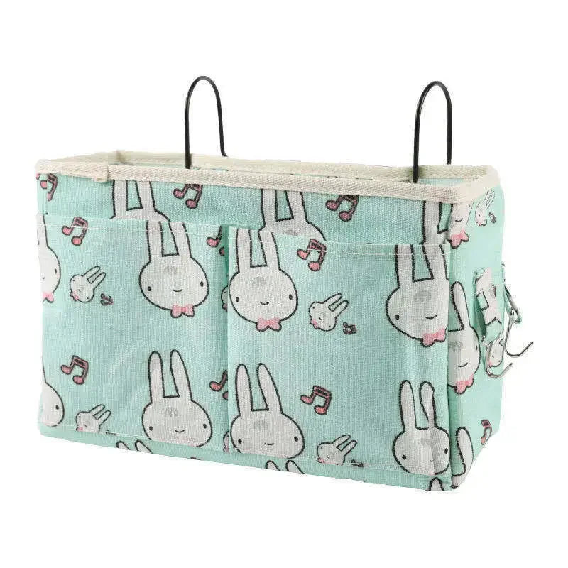 Mint green cotton multi-pocket crib organizer with white bunny and music note print, featuring two metal hooks.