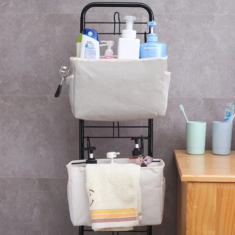 Two-tier hanging storage organizer with light gray fabric bins and mesh pockets, holding toiletries and a towel.