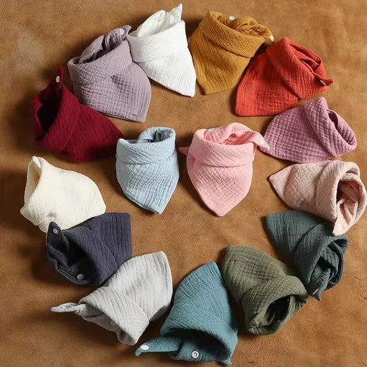 Assorted cotton baby bibs in various colors, triangular design, with snap buttons.