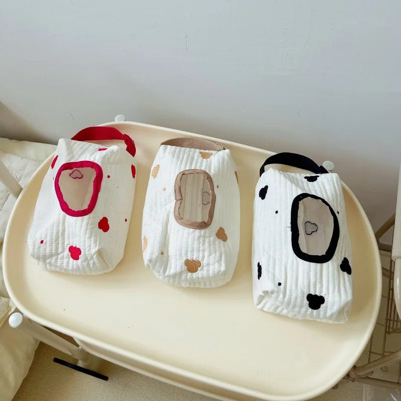 Three hanging cotton tissue and wipe holders in white, featuring red hearts, brown spots, and black cow print designs.