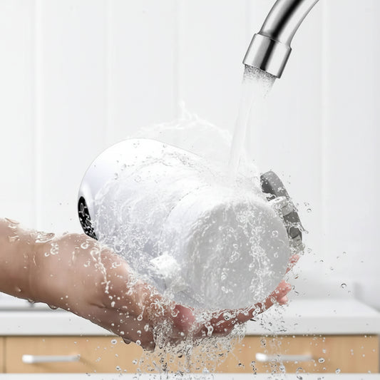 White portable bottle warmer, IPX6 washable, held under running water from a silver faucet.