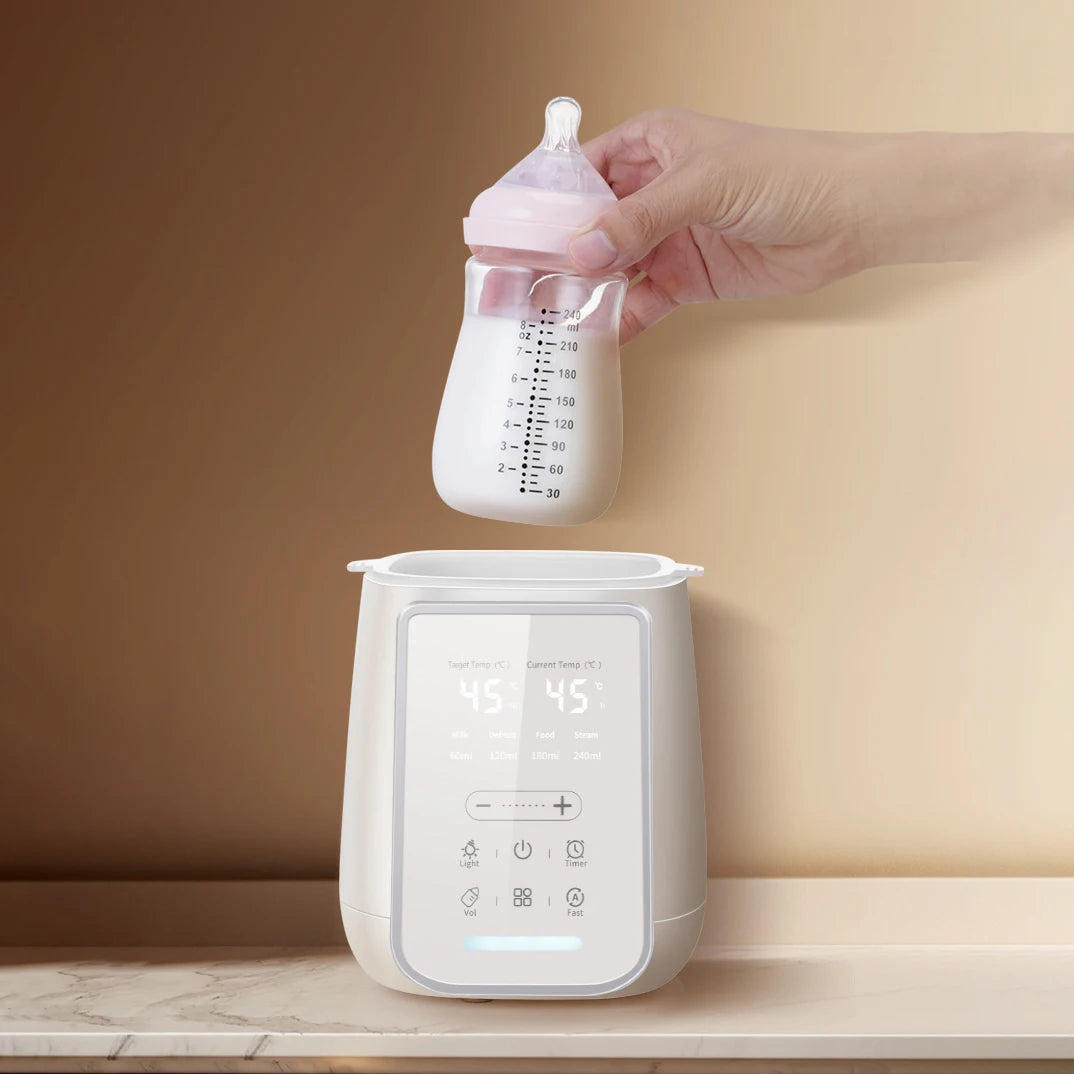 White baby bottle warmer and sterilizer with a digital display, as a hand places a pink-capped bottle inside.