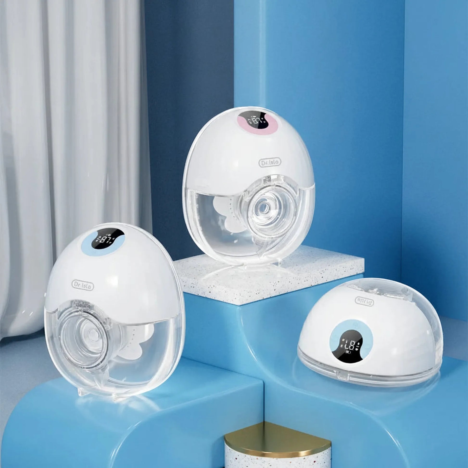 Three white and clear wearable electric breast pumps, two upright with digital displays, one disassembled.