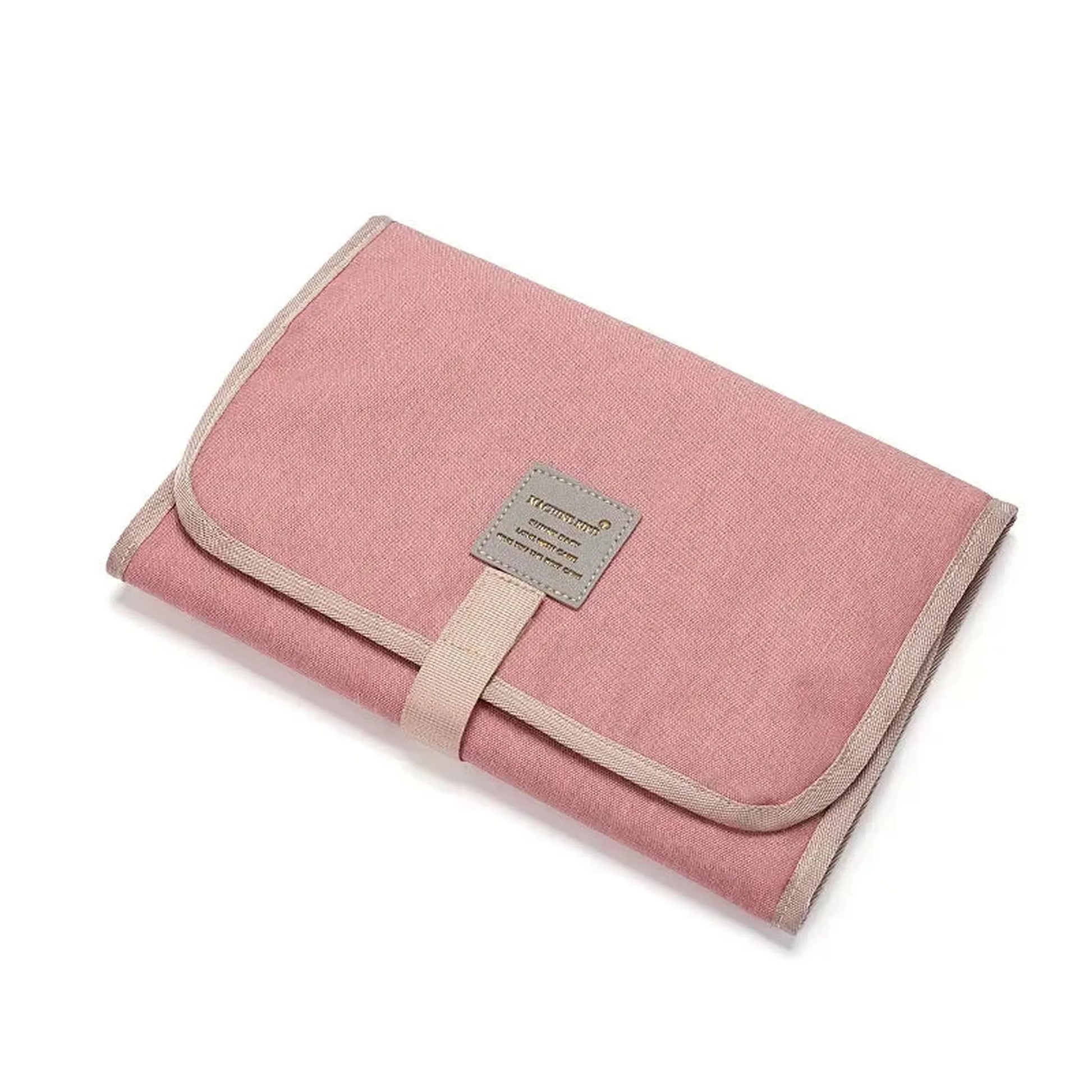 Pink portable waterproof baby changing pad with beige trim, strap, and brand tag.