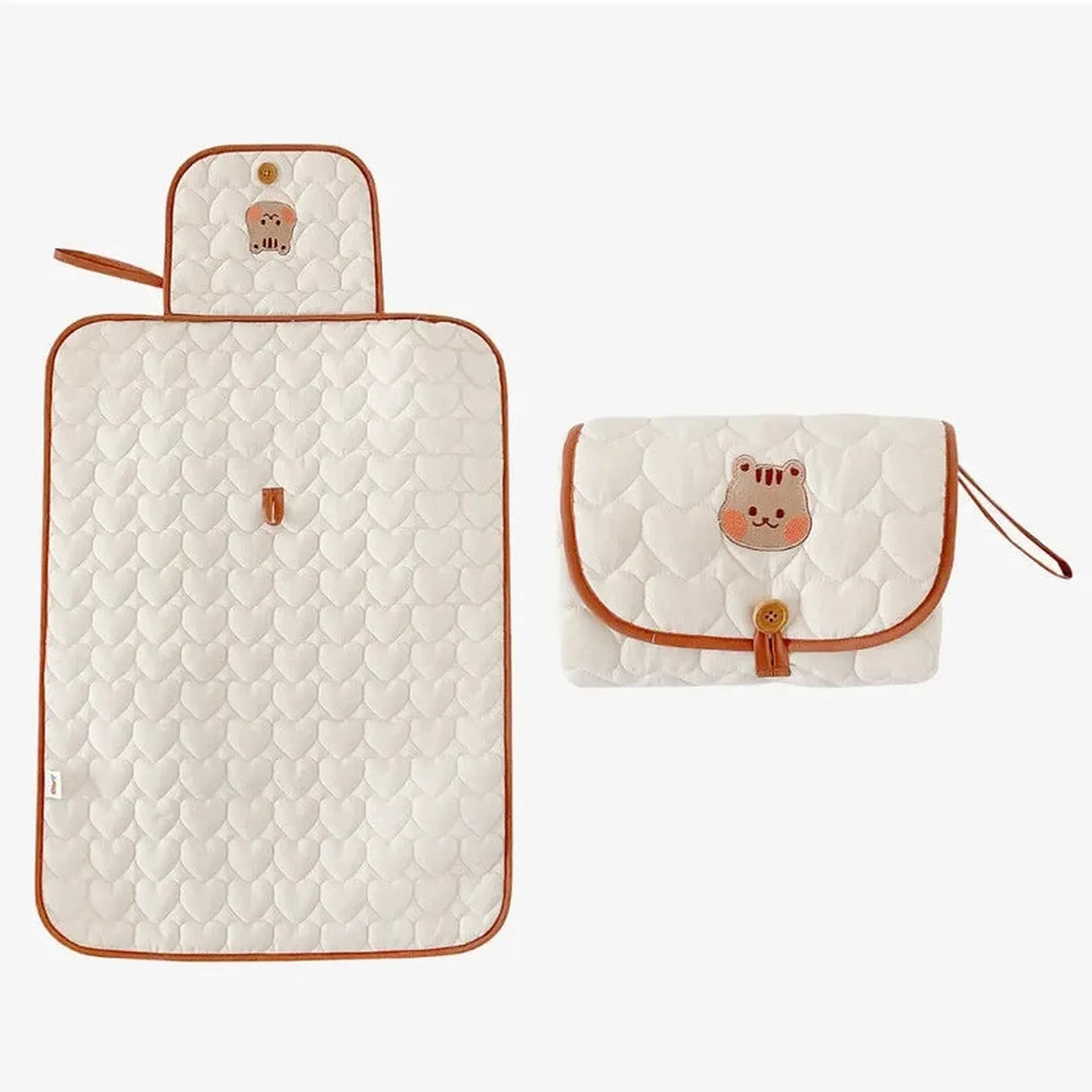 Quilted white portable changing pad with heart pattern and brown trim, shown open and folded with a cute bear design.