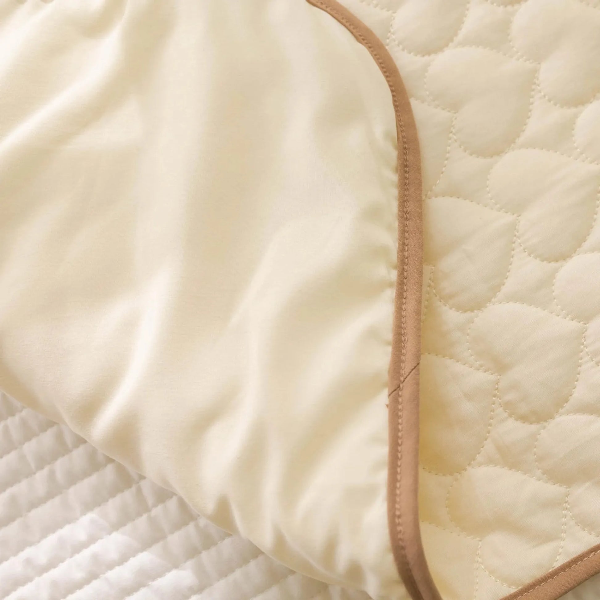 Close-up of a cream portable, waterproof changing pad with a soft cotton top and quilted heart pattern.