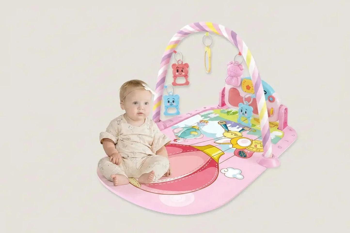 Baby on a pink musical play mat with a piano, colorful arch, and hanging animal toys.
