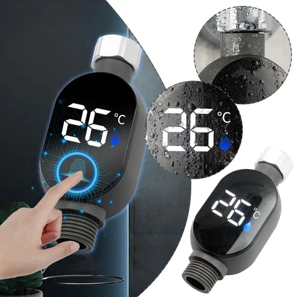 Black digital shower thermometer with LED display showing 26°C and a finger touching the screen.