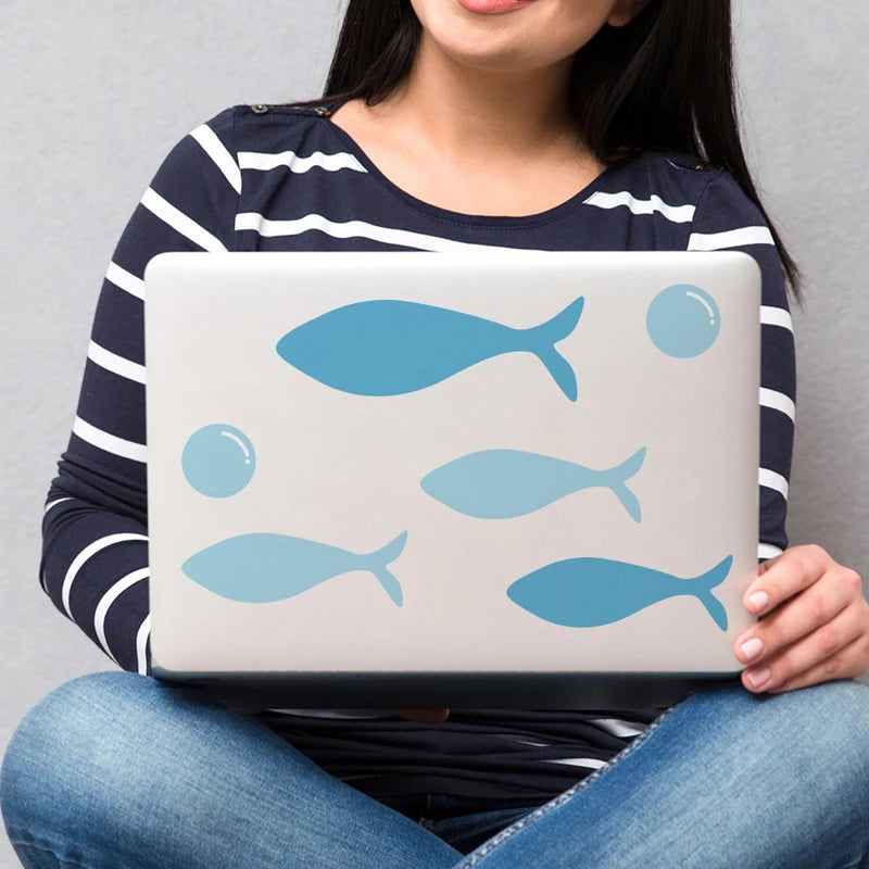 Blue PVC sea fish wall decals on a laptop, featuring various fish and bubble designs for kids' rooms.
