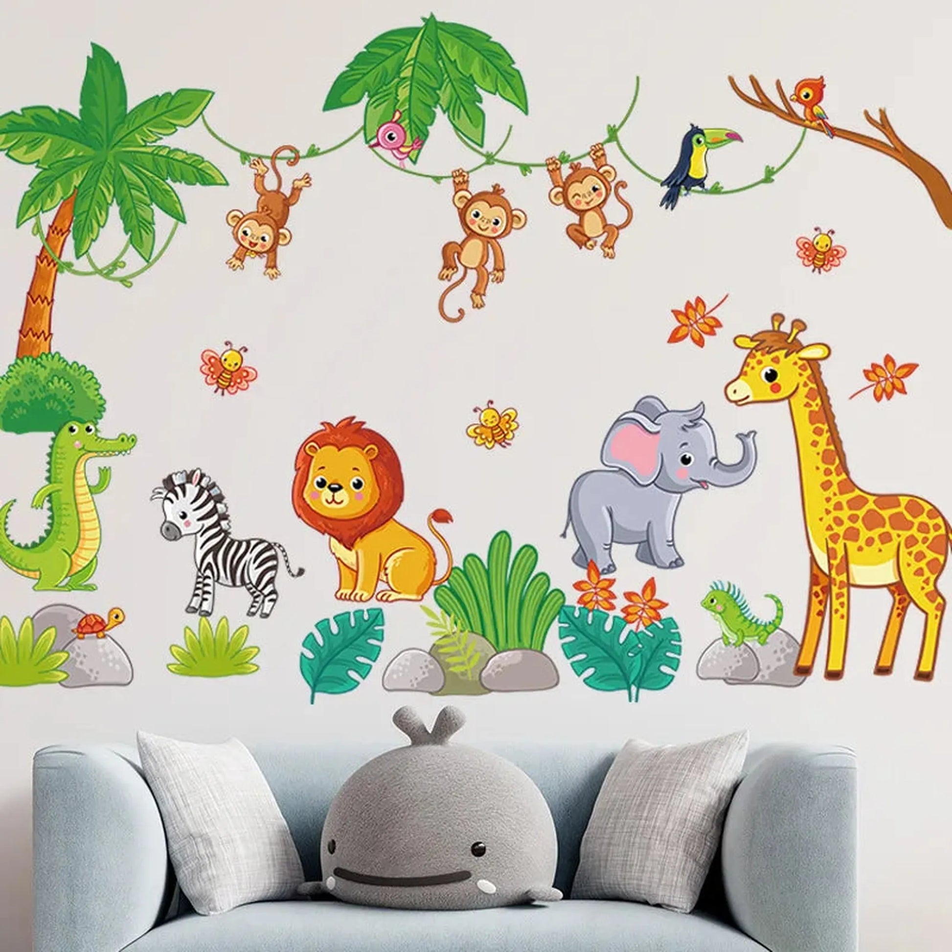 Colorful PVC jungle animal wall decals with monkeys, lion, elephant, giraffe, zebra, and crocodile above a blue sofa.