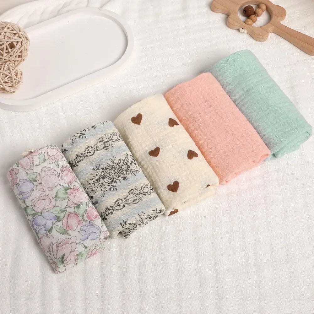 Soft 100% cotton gauze baby towels in pastel pink, mint, cream with hearts, floral, and striped patterns.