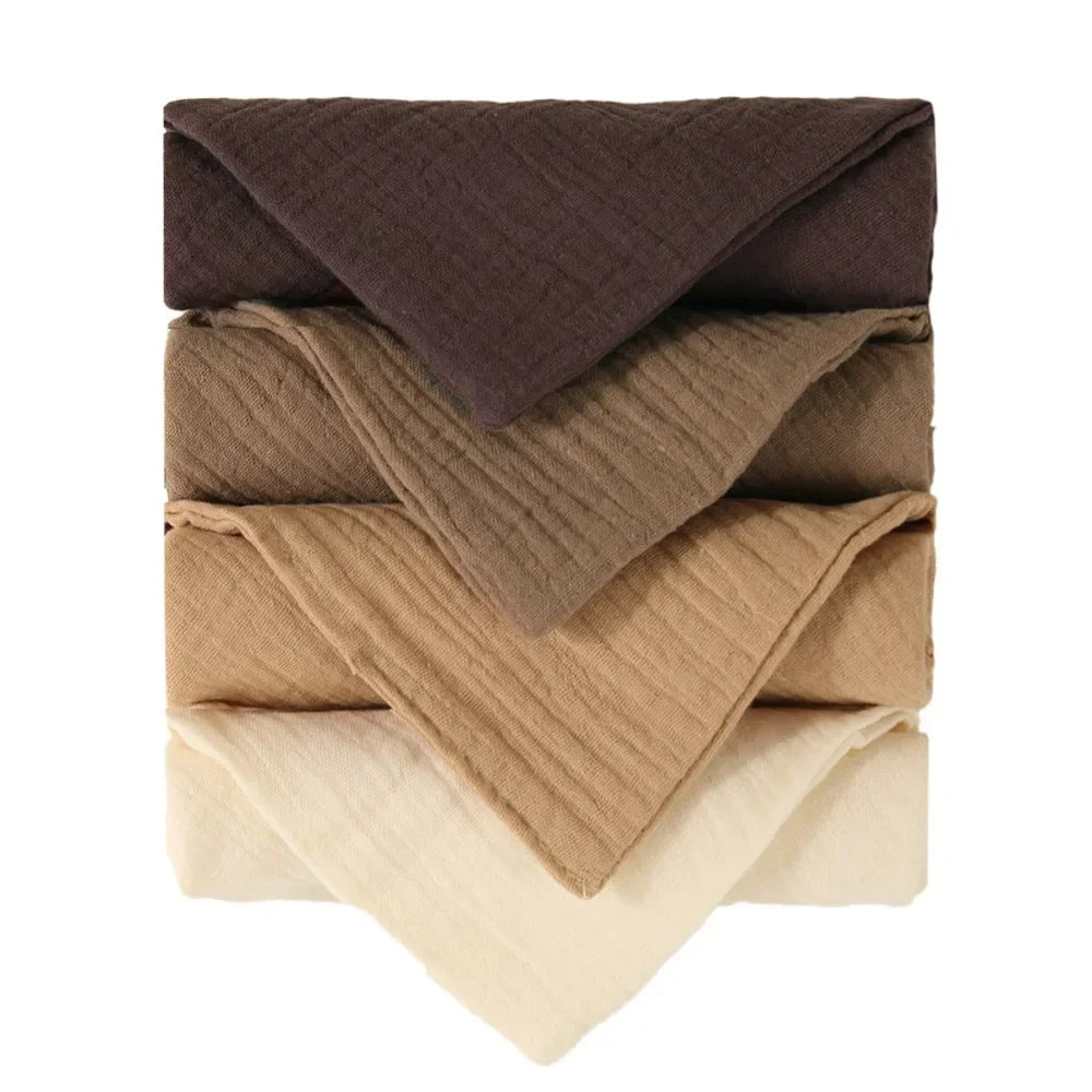 Stack of five folded baby gauze cotton towels in shades of brown, beige, and cream.