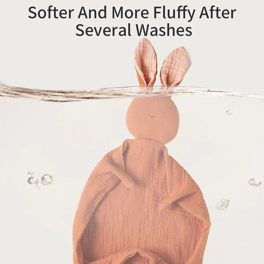 Soft peach muslin baby comfort blanket with bunny ears, shown partially submerged in water.
