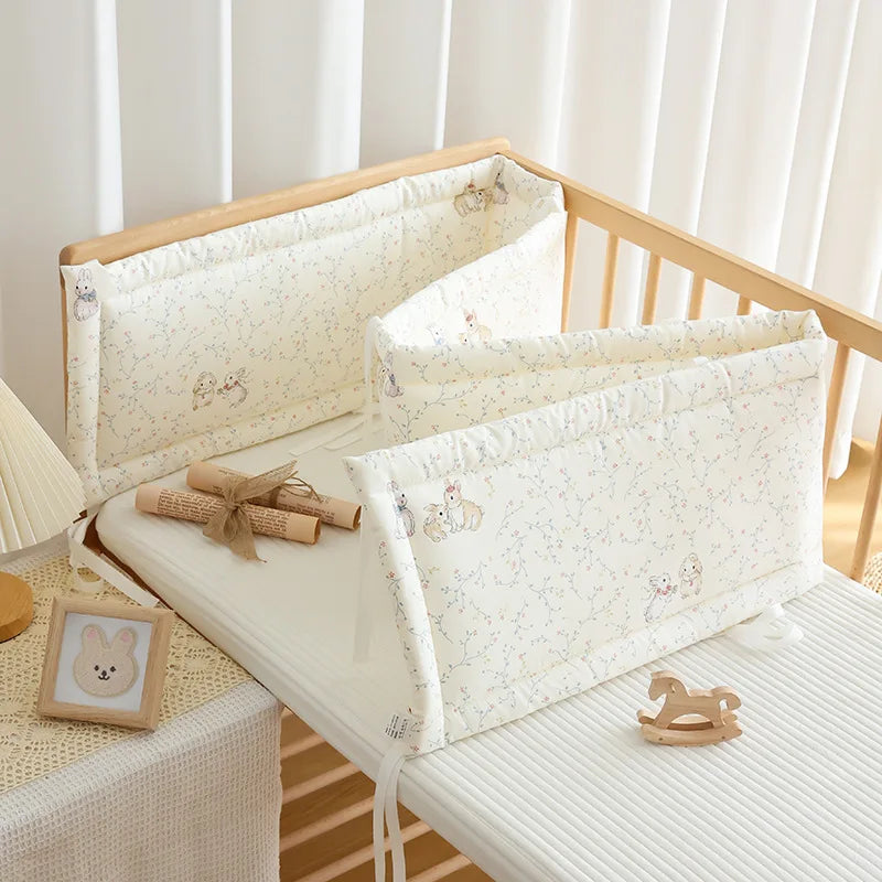 Soft white polyester crib bumper with rabbit and bear print, providing gentle protection.