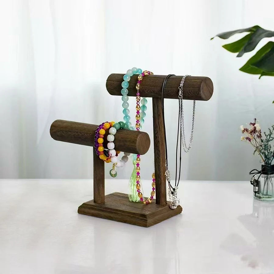 Dark brown wooden jewelry organizer stand with two T-bars holding necklaces and beaded bracelets.