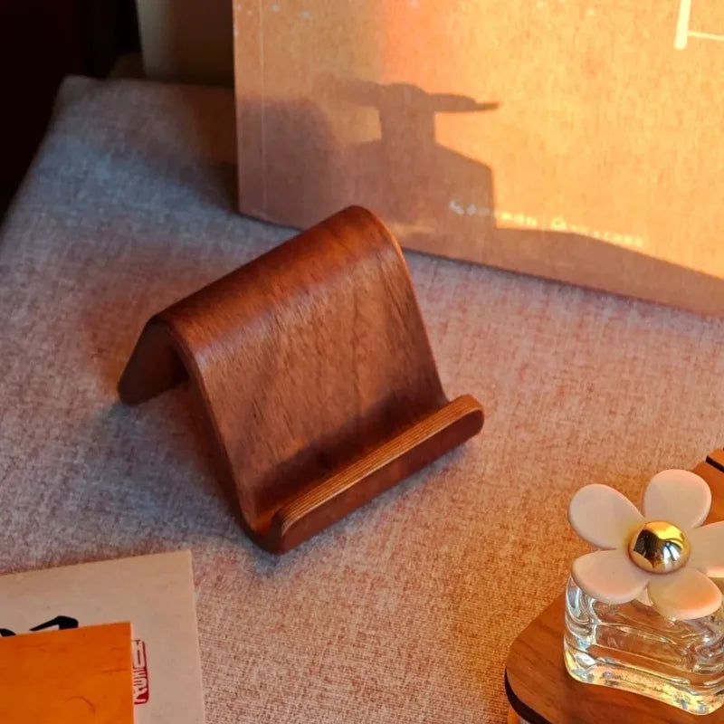 Minimalist dark walnut wood phone stand and business card holder on a desk.