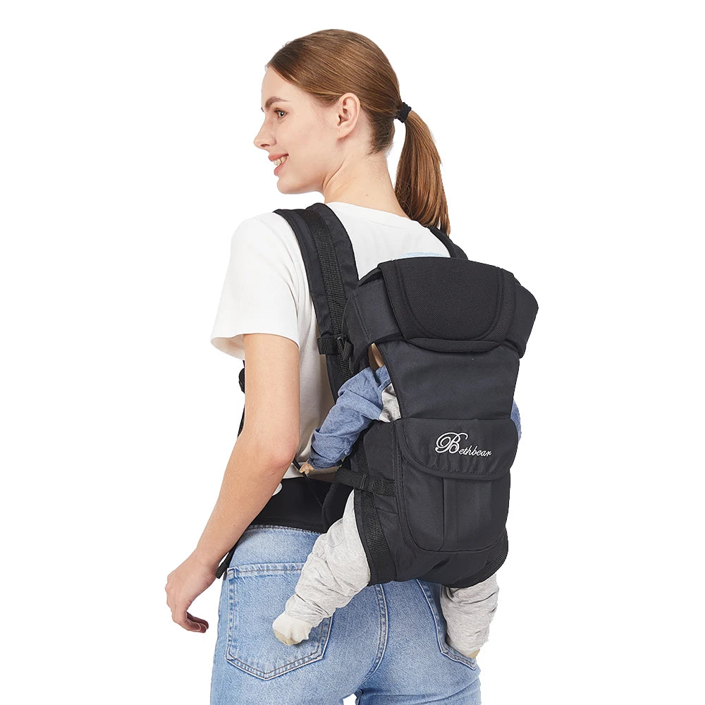 Woman wearing a black ergonomic baby carrier with a baby on her back, featuring padded straps and breathable fabric.
