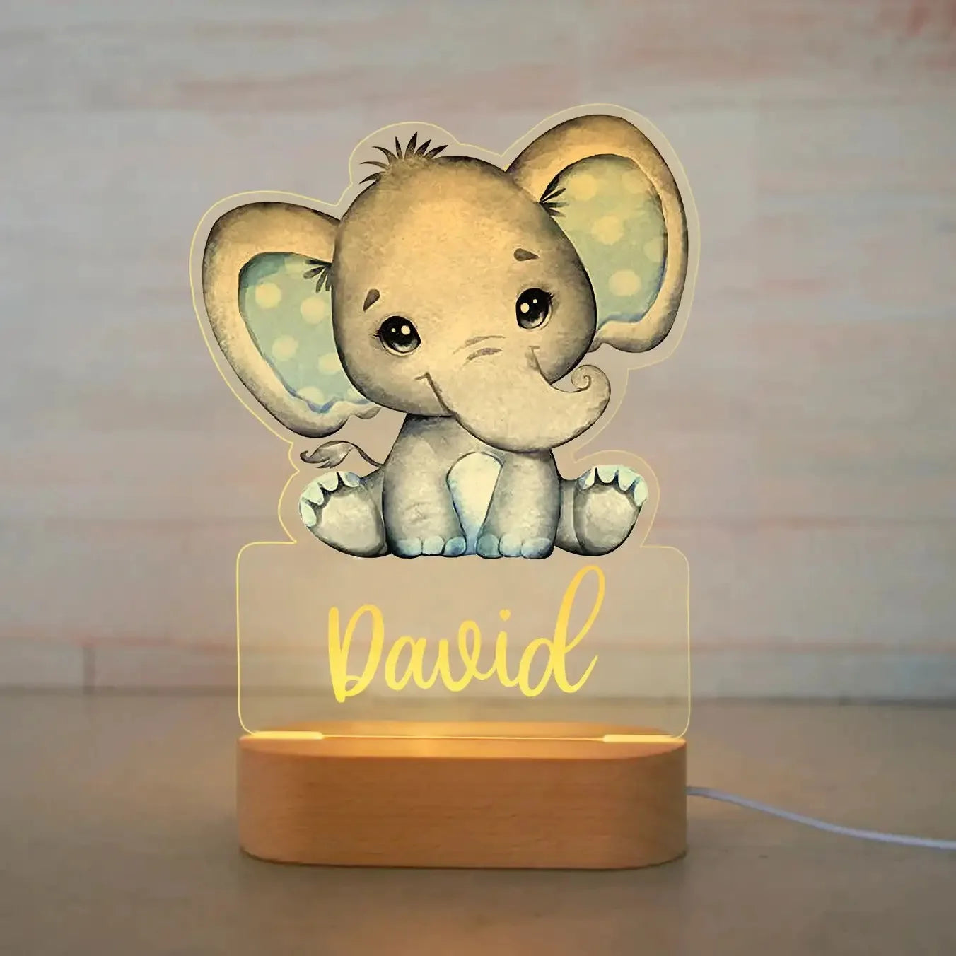 Personalized LED night light with a cute elephant design, acrylic panel, and wooden base, glowing with a child's name.