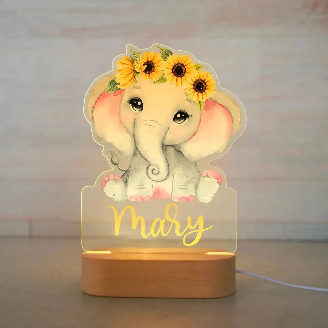 Personalized acrylic elephant night light with sunflowers and "Mary" on a wooden base.