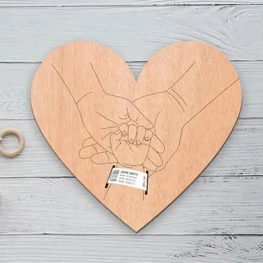 Heart-shaped wooden plaque with engraved hands holding a baby's ultrasound, 12x18 cm, minimalist design.