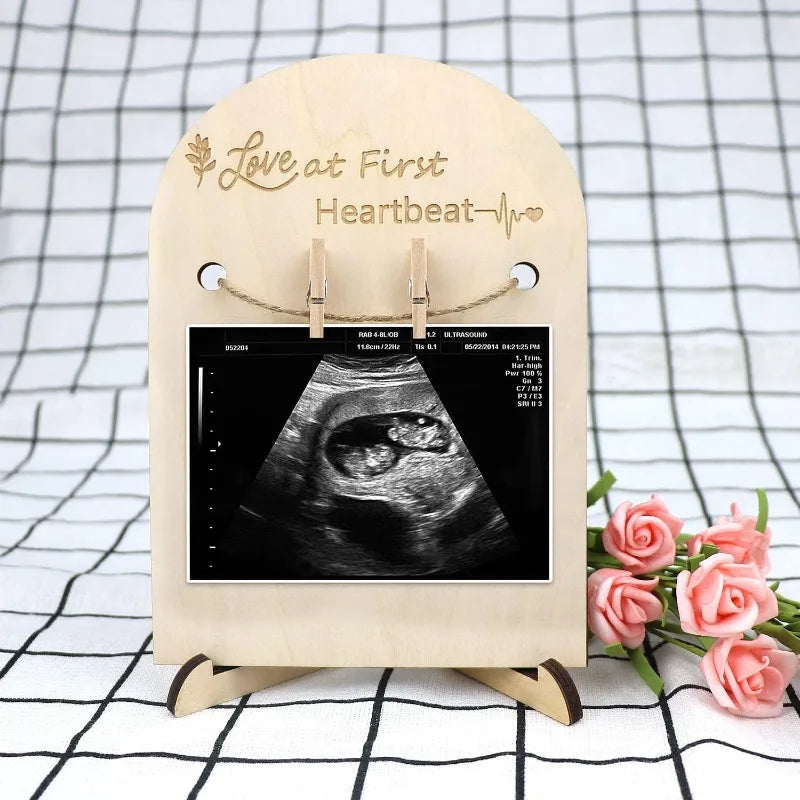 Minimalist natural wood ultrasound photo frame with "Love at First Heartbeat" engraving, holding a baby scan.