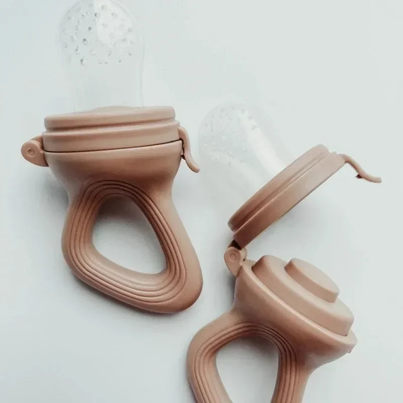 Two pink silicone baby fruit feeders with clear textured nipples and easy-grip handles.