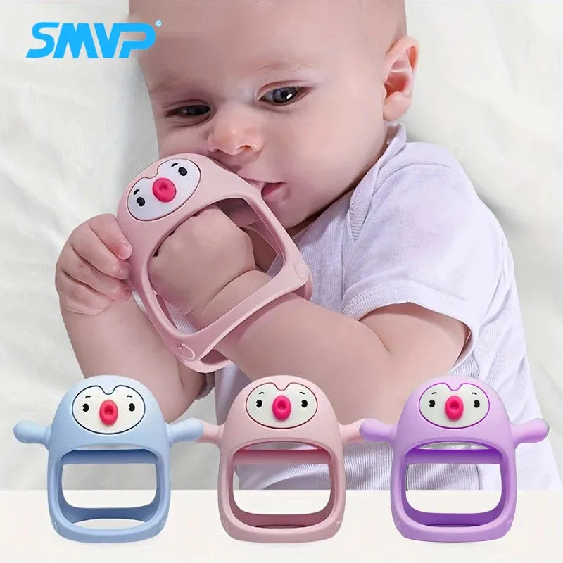 Baby chewing pacifier in pink, blue, and purple penguin designs, held by a baby.