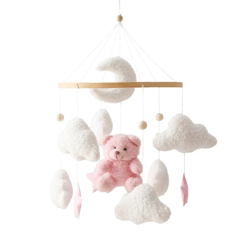 Wooden crib mobile with pink teddy bear, white clouds, moon, and stars.